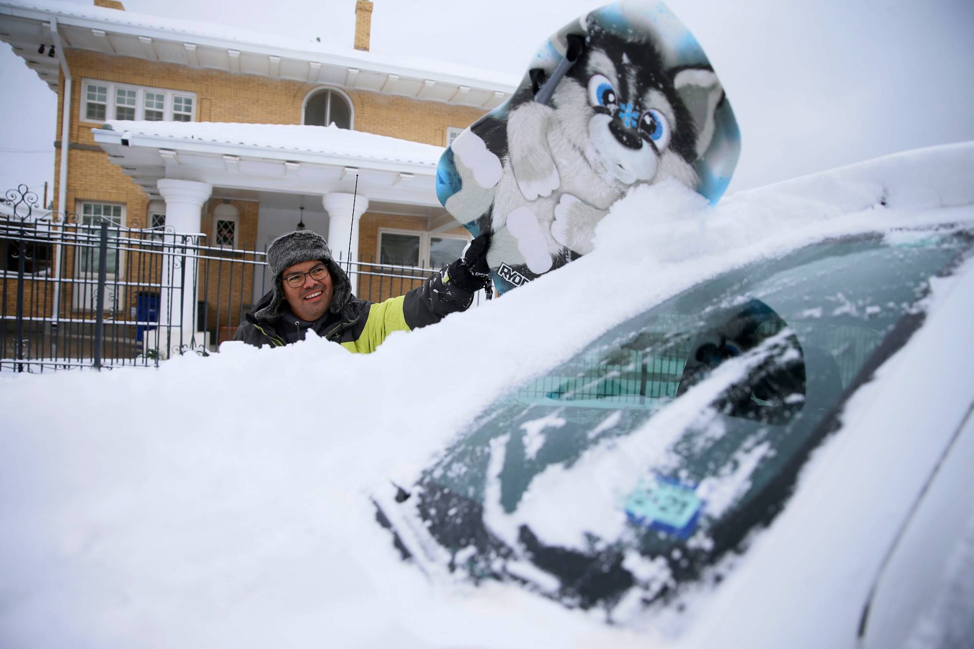 Francisco Sanchez wipes snow off his car with a boogie board in El Paso, Texas, on Sunday. | El Paso Times / USA Today Network / via REUTERS
