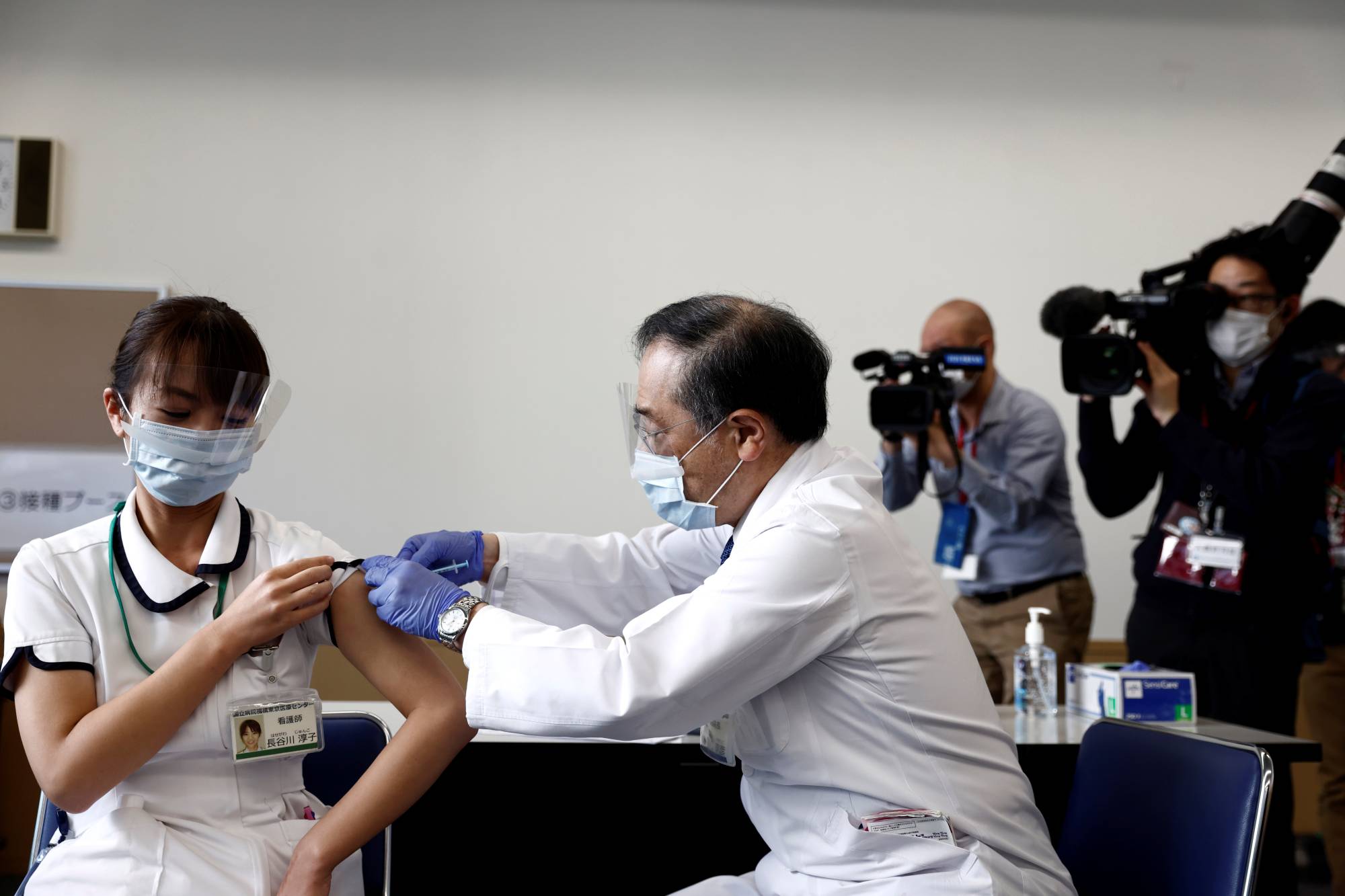 A medical worker receives a dose of the COVID-19 vaccine as Japan launches its inoculation campaign, at Tokyo Medical Center on Wednesday. | POOL / VIA REUTERS