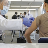 A medical worker is given a COVID-19 vaccine on Wednesday at the National Hospital Organization Tokyo Medical Center in Tokyo\'s Meguro Ward. | POOL 