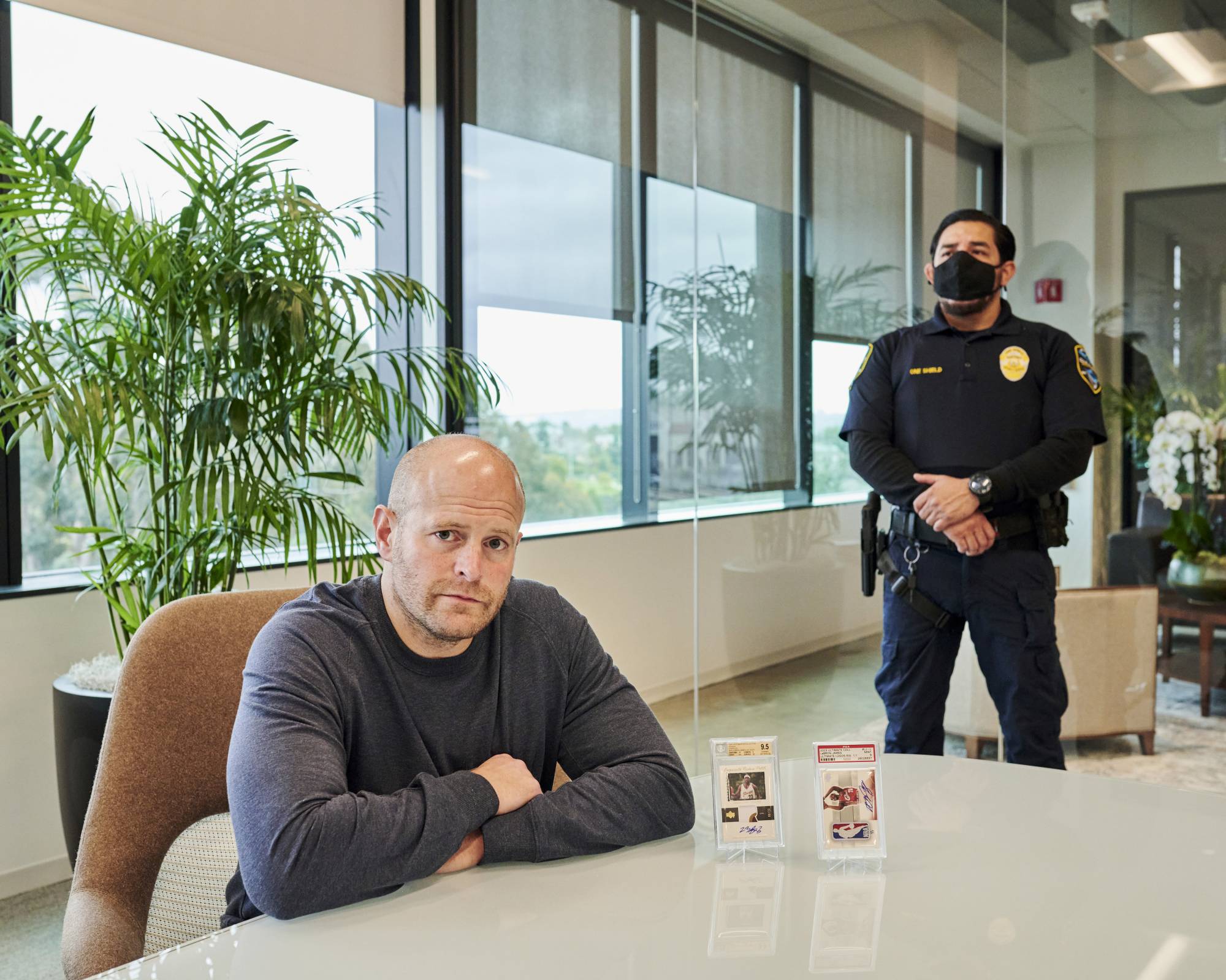 Aaron Davis visits his two LeBron James cards, seen on the table, with a security guard present at a bank in San Diego on Feb. 13. | JOHN FRANCIS PETERS / THE NEW YORK TIMES