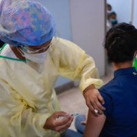 A health worker applies a dose of the Sputnik V vaccine against COVID-19 to a staff member of the University Clinical Hospital in Caracas on Friday amid the novel coronavirus pandemic. | AFP-JIJI