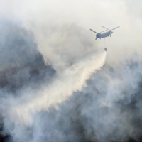 A helicopters dumps water on a wildfire in Ashikaga in Tochigi Prefecture on Wednesday. The fire was reported by a hiker three days earlier.  | KYODO
