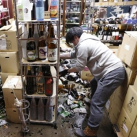 Bottles are scattered on the floor at a liquor shop in the city of Fukushima where a powerful earthquake hit on Feb. 13. The city announced its first fatality due to the quake on Thursday. | REUTERS 