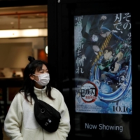 People walk past a poster for the animated movie \"Demon slayer\" in December. | REUTERS