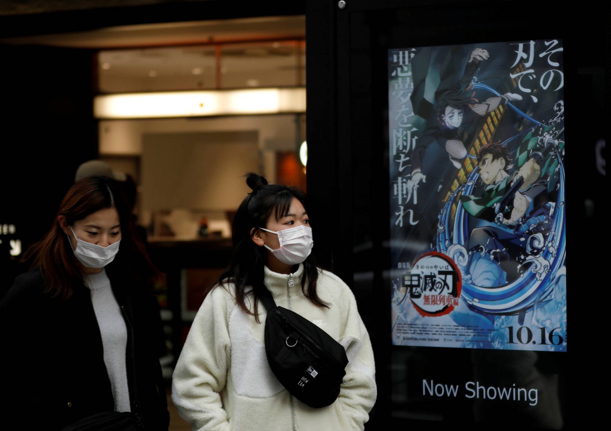 People walk past a poster for the animated movie 'Demon slayer' in December. | REUTERS