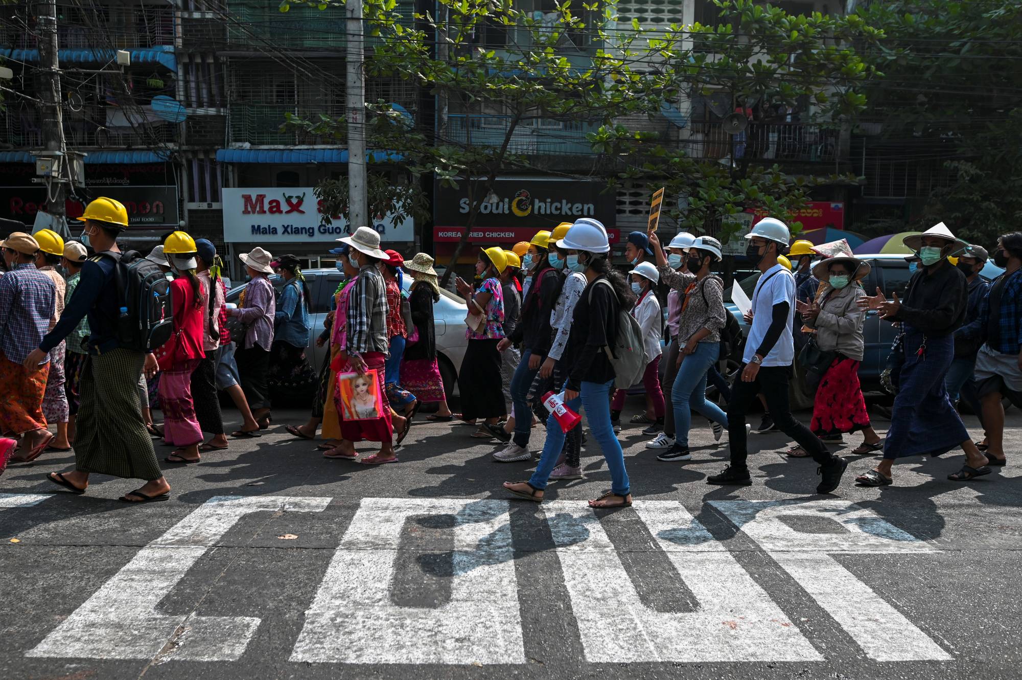 Demonstrators rally against the military coup and show their support to local residents Friday in the Tamwe neighborhood of Yangon, after riot police officers used teargas the previous night to disperse a crowd of protesters. | REUTERS