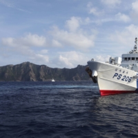 A Japan Coast Guard vessel sails in front of Uotsuri Island, one of the disputed Senkaku islets in the East China Sea, in August 2013. | REUTERS