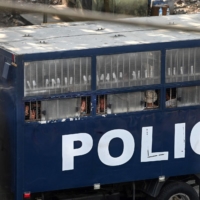 Protesters make three-finger salutes from a police truck in Yangon on Saturday.  | AFP-JIJI
