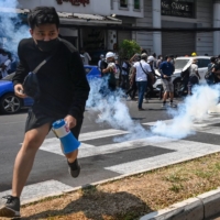 Protesters run after police fired tear gas to disperse them during a demonstration against the military coup in Yangon on Sunday.  | AFP-JIJI