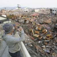 A man surveys the damage in Ishinomaki, Miyagi Prefecture, a few days after the city was struck by a deadly tsunami in March 2011. | KYODO