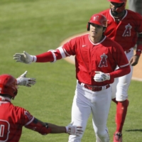 The Angels\' Shohei Ohtani is congratulated by teammates after hitting a two-run home run against the Rangers in Tempe, Arizona, on Wednesday. | KYODO