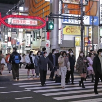 People wearing face masks walk in Tokyo\'s Shinjuku area on Saturday, a day after the Japanese government extended the COVID-19 state of emergency for Tokyo and three neighboring prefectures for two weeks.  | KYODO 