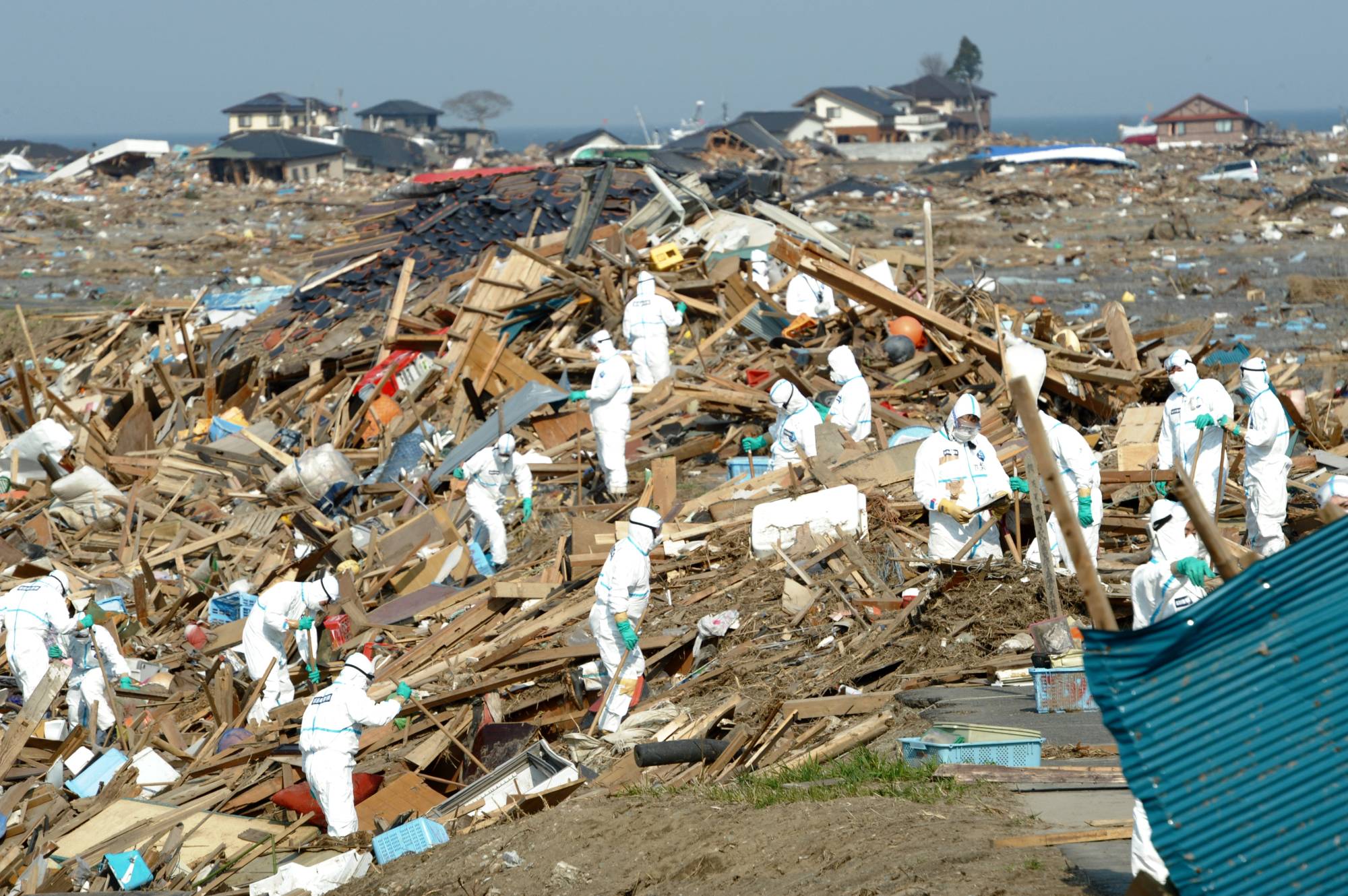 Disaster response workers search for missing people in the Ukedo district of the town of Namie, Fukushima Prefecture, on April 14, 2011. That day, they found 10 bodies. | TADAO FURUKAWA / COURTESY OF FUKUSHIMA MINPO