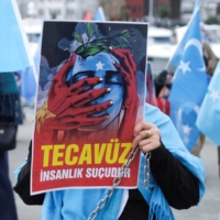 An ethnic Uyghur demonstrator holds a placard that reads: \"Rape is crime against humanity\" during a demonstration in Istanbul on Monday to protest China\'s treatment of Uyghurs. | REUTERS 