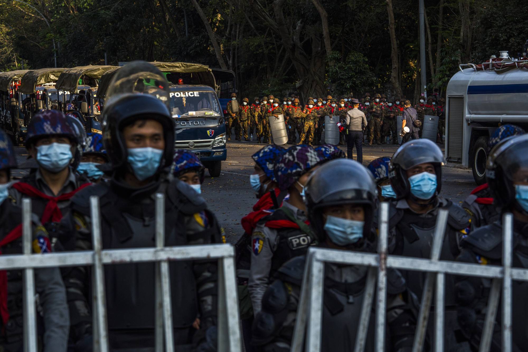 Police and military forces stand by on Feb. 9 in Yangon, Myanmar, as tens of thousands of people gather on University Avenue Road to protest against the military's seizure of power. | The New York Times