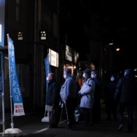 Customers wait in line outside a coronavirus testing site in the Akihabara shopping district of Tokyo on Feb. 24. | BLOOMBERG