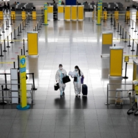 Passengers wearing hazmat suits for protection against the coronavirus at Ninoy Aquino International Airport in Paranaque, Metro Manila, in January.  | REUTERS