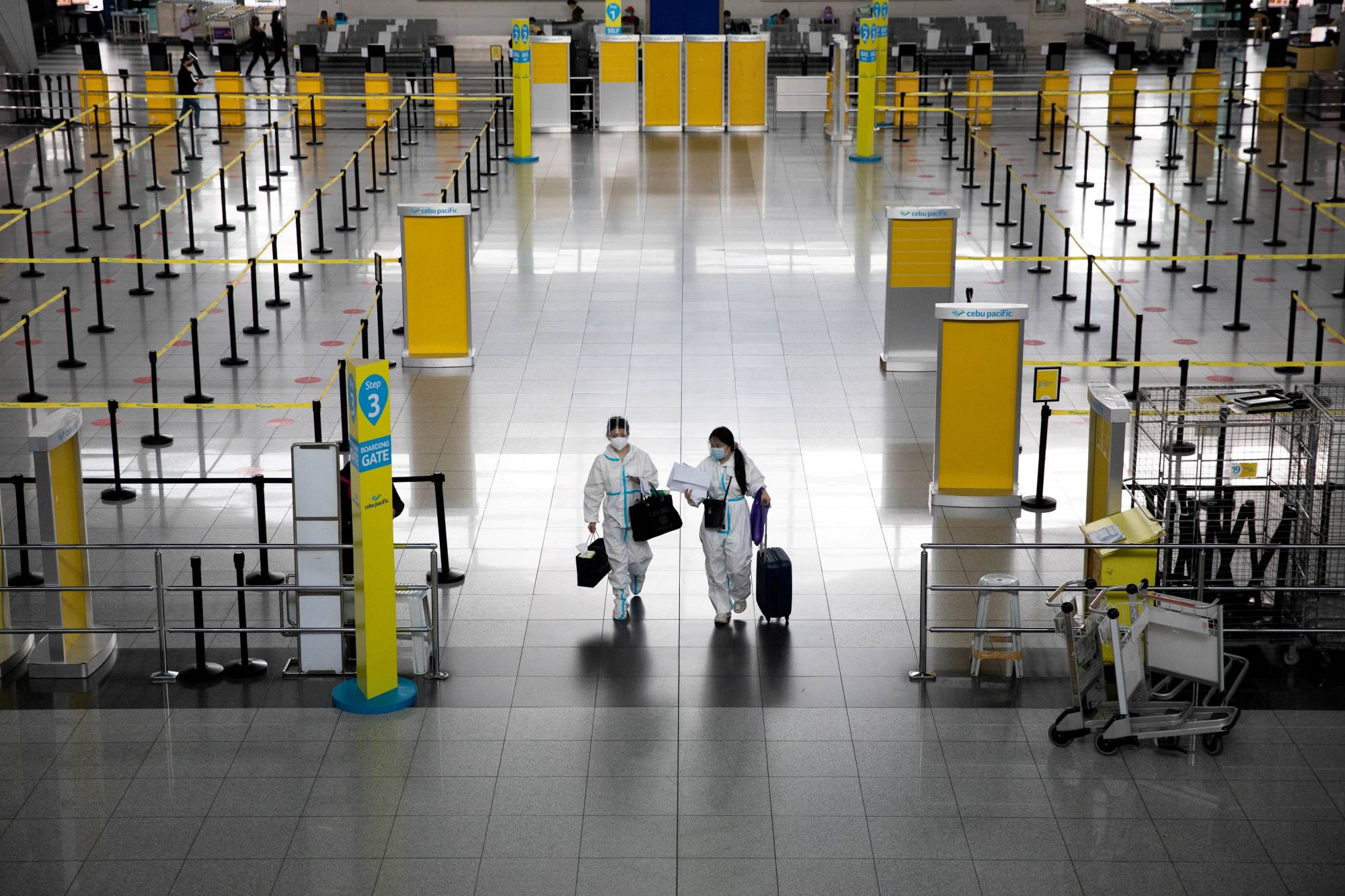 Passengers wearing hazmat suits for protection against the coronavirus at Ninoy Aquino International Airport in Paranaque, Metro Manila, in January. | REUTERS