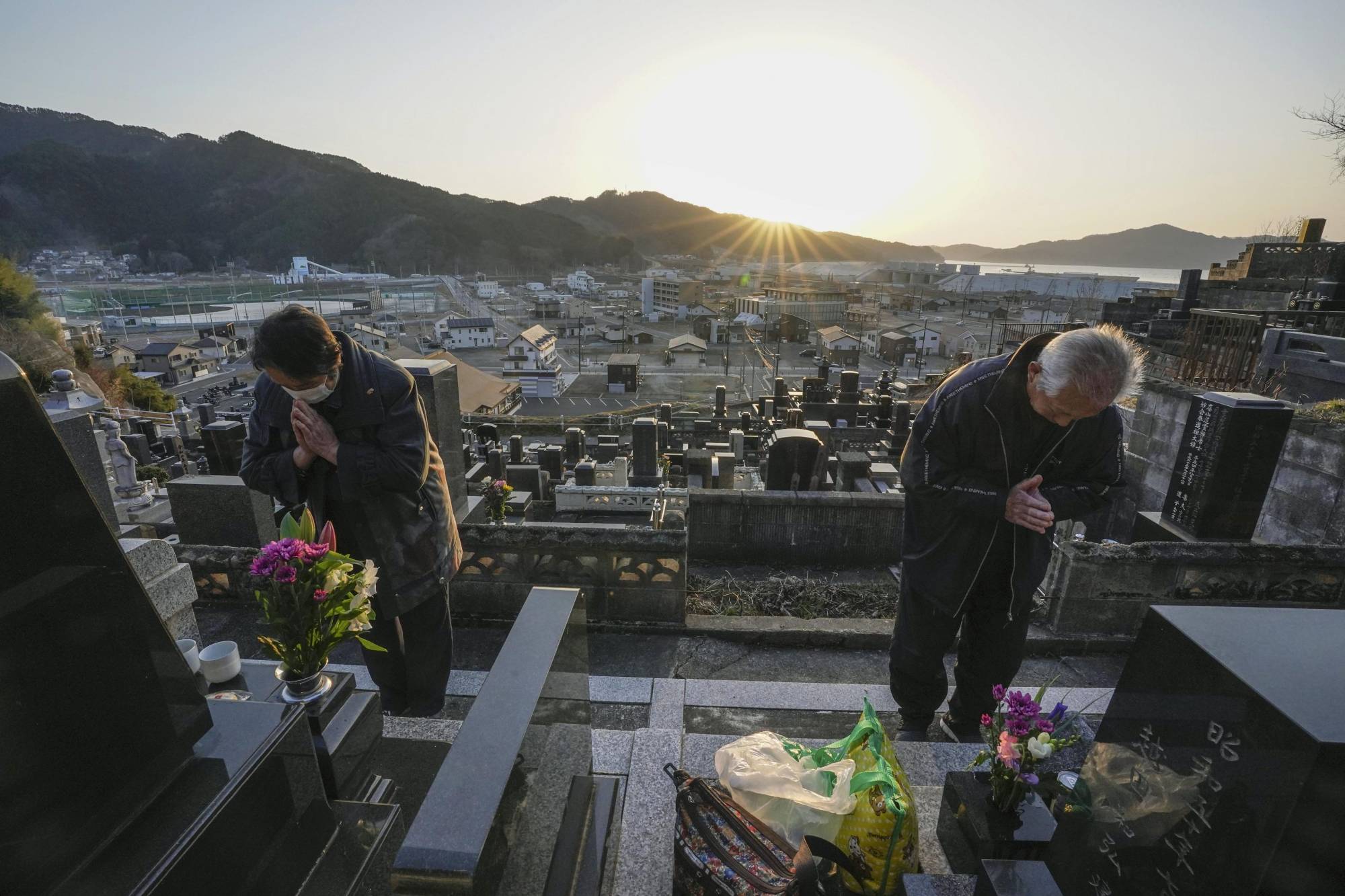 A man and his wife pray for relatives at a grave in Otsuchi, Iwate Prefecture, on Thursday. The couple say they still can't come to terms with the lives lost. | KYODO