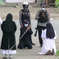 Nun Ann Rose Nu Tawng kneels in front of police officers as she asks security forces to refrain from violence against children and residents amid protests in Myitkyina, Myanmar, on March 9. | MYITKYINA NEWS JOURNAL / VIA REUTERS