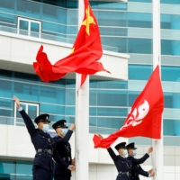 Police officers gesture next to the Chinese and Hong Kong flags at a flag-raising ceremony in the city on Thursday. | REUTERS
