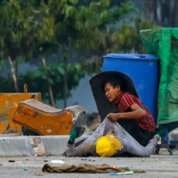 A protester holds onto the shirt of a fallen comrade, during a crackdown by security forces on demonstrations against the military coup, in the Hlaing Tharyar township of Yangon, Myanmar, on Sunday. | AFP-JIJI