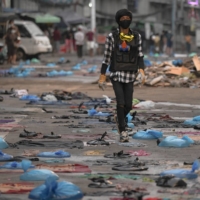 A protester walks in a street full of water bags to be used against tear gas, during an anti-coup protest at Hledan junction in Yangon, Myanmar, on Sunday. | REUTERS