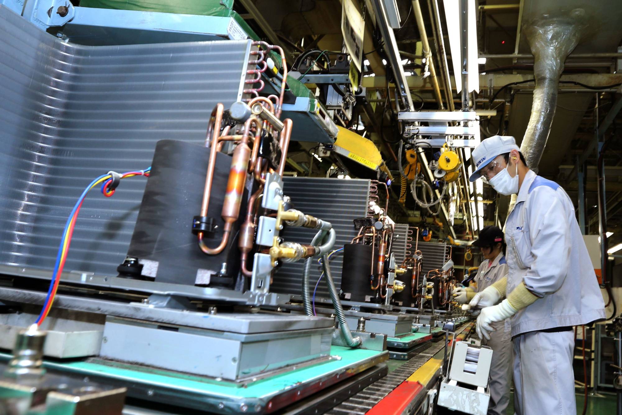 Workers assemble outdoor air conditioner units on the production line of Daikin Industries Ltd.'s plant in Kusatsu, Shiga Prefecture, in August 2017. | BLOOMBERG 