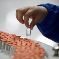 A worker performs a quality check in a packaging facility of Chinese vaccine-maker Sinovac Biotech during a government-organized media tour in Beijing in September 2020.  | REUTERS 