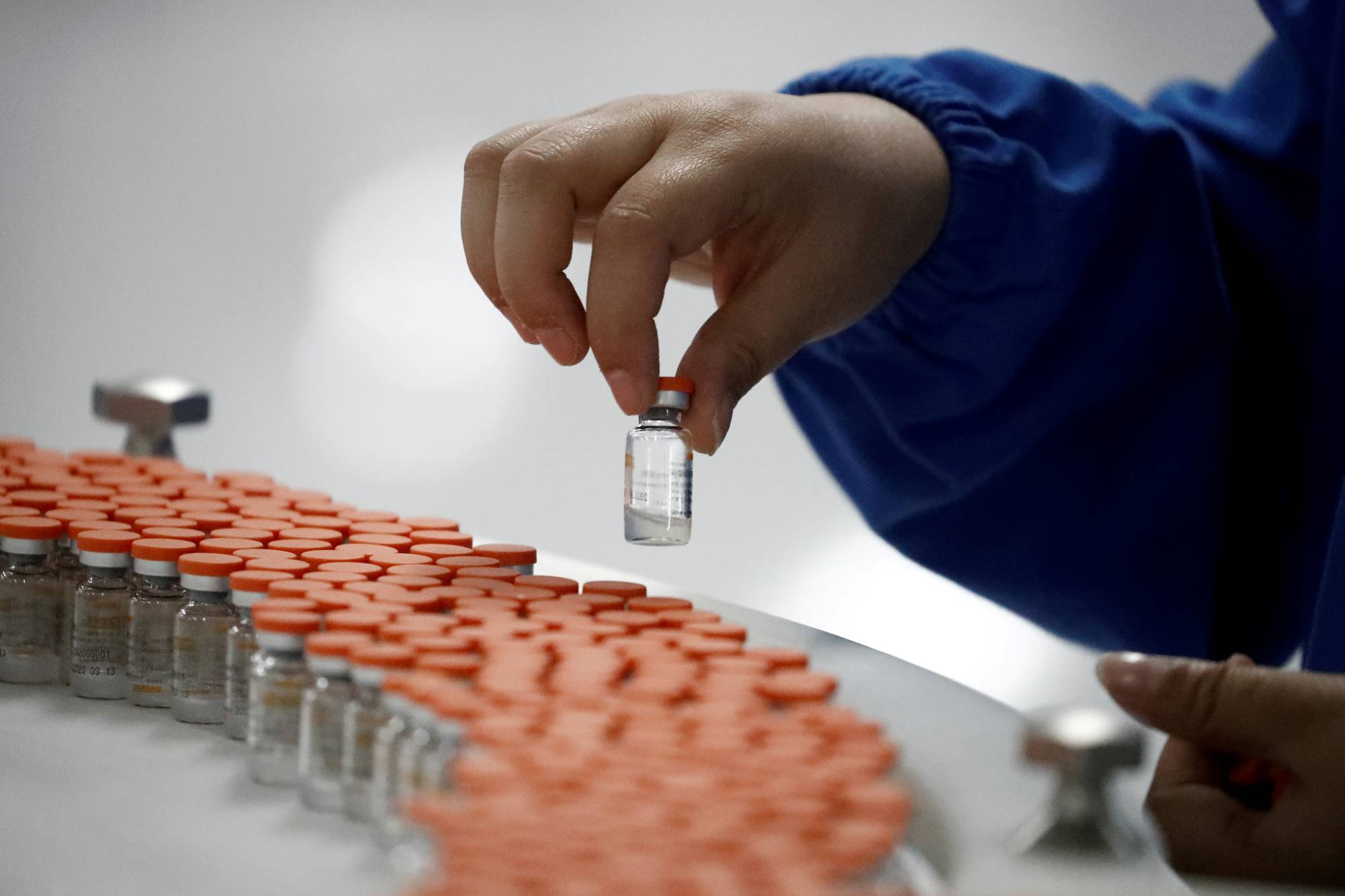 A worker performs a quality check in a packaging facility of Chinese vaccine-maker Sinovac Biotech during a government-organized media tour in Beijing in September 2020.  | REUTERS 