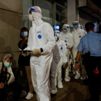 Workers arrive at a locked-down part of Sai Ying Pun to contain a new outbreak of COVID-19 in Hong Kong on Monday. | REUTERS 