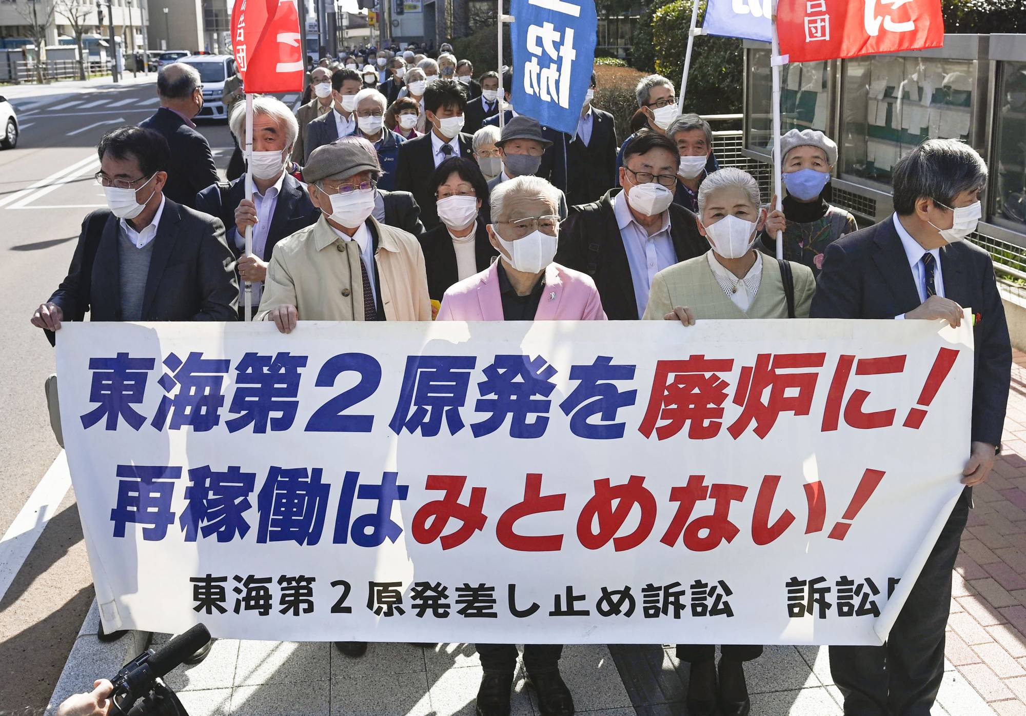 Plaintiffs hold a sign saying they oppose restarts at the Tokai No. 2 nuclear power plant as they head to a court ruling in Mito, Ibaraki Prefecture, on Thursday. | KYODO