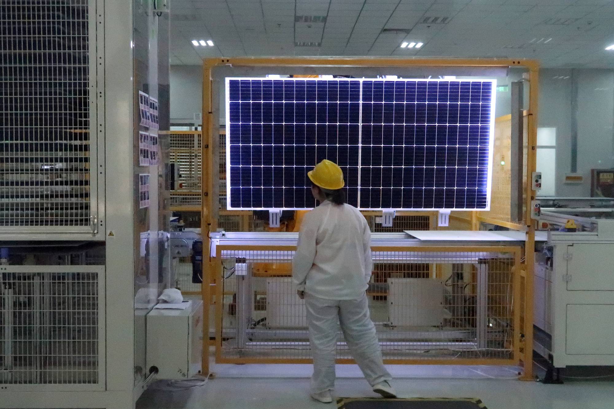 A worker conducts a quality-check of a solar module product at a factory in Xian, China. | Reuters
