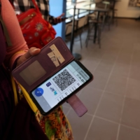 A woman shows her COVID-19 vaccination status on her mobile phone at a gym, where a \"green passport\" is required to enter, in Tel Aviv in February. | REUTERS