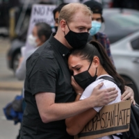 Demonstrators embrace during a rally Thursday calling attention to the rise in violence against Asian Americans, outside Gold Spa near Acworth, Georgia, one of three establishments targeted in a mass shooting earlier this week.  | CHANG W. LEE / THE NEW YORK TIMES