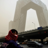 A woman is seen in front of the headquarters of the state-run broadcaster China Central Television in Beijing on March 15. Some bloggers are finding big audiences among Chinese citizens who are skeptical of both Western narratives and state-run mouthpieces. | REUTERS