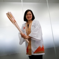 Hiromi Kawamura, senior director of planning and international coordination for the Tokyo Olympic torch relay, holds the Tokyo 2020 torch during an interview in Tokyo on Friday. | REUTERS
