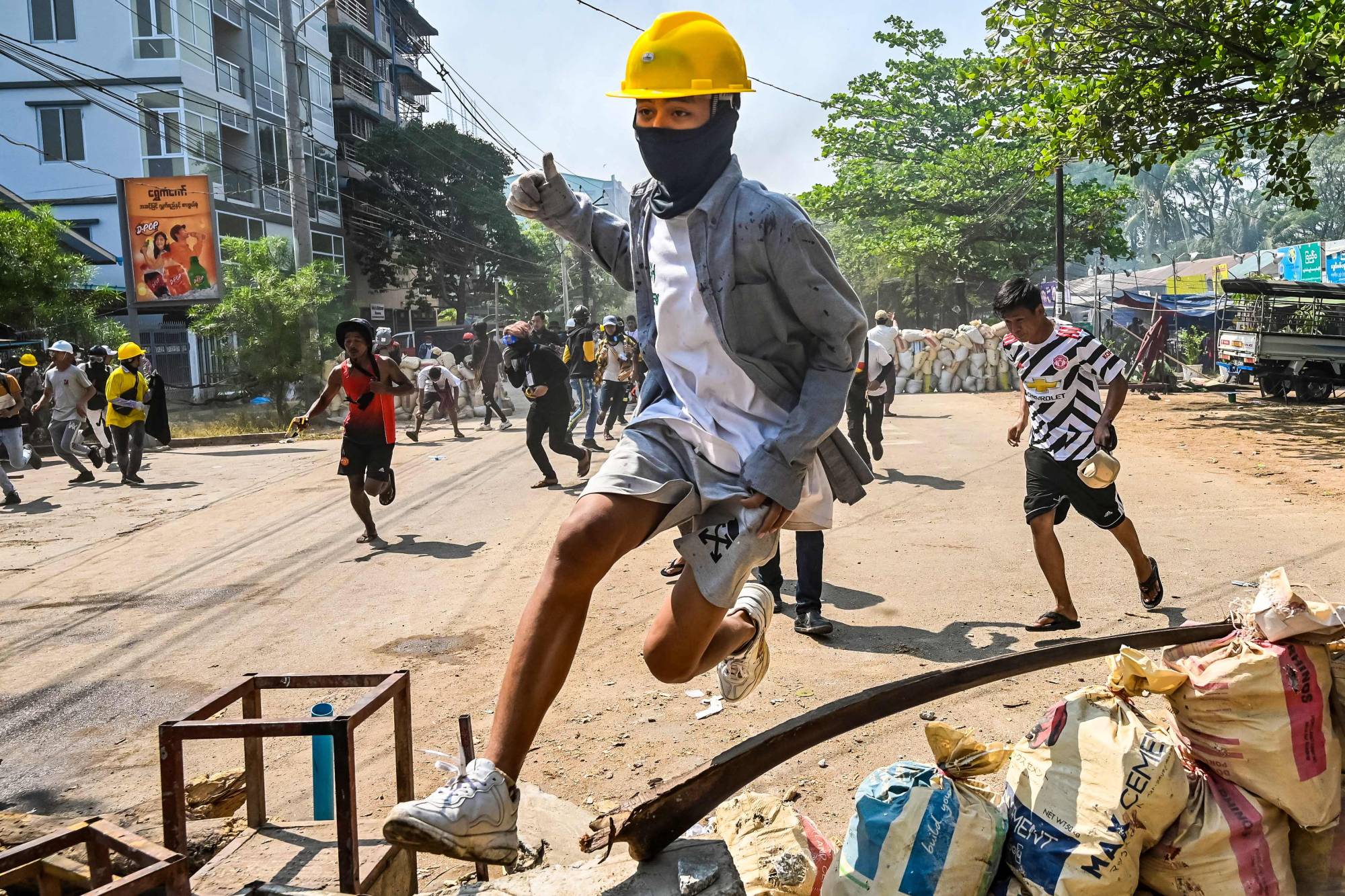 A protester jumps over a makeshift barricade during a crackdown by security forces in Yangon's Thaketa township on Friday. | AFP-Jiji