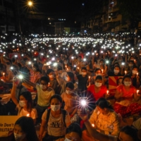Protesters hold up their mobile phones as they take part in a candlelight vigil to honor those who have died during demonstrations against the military coup, in Yangon on March 13. | AFP-JIJI