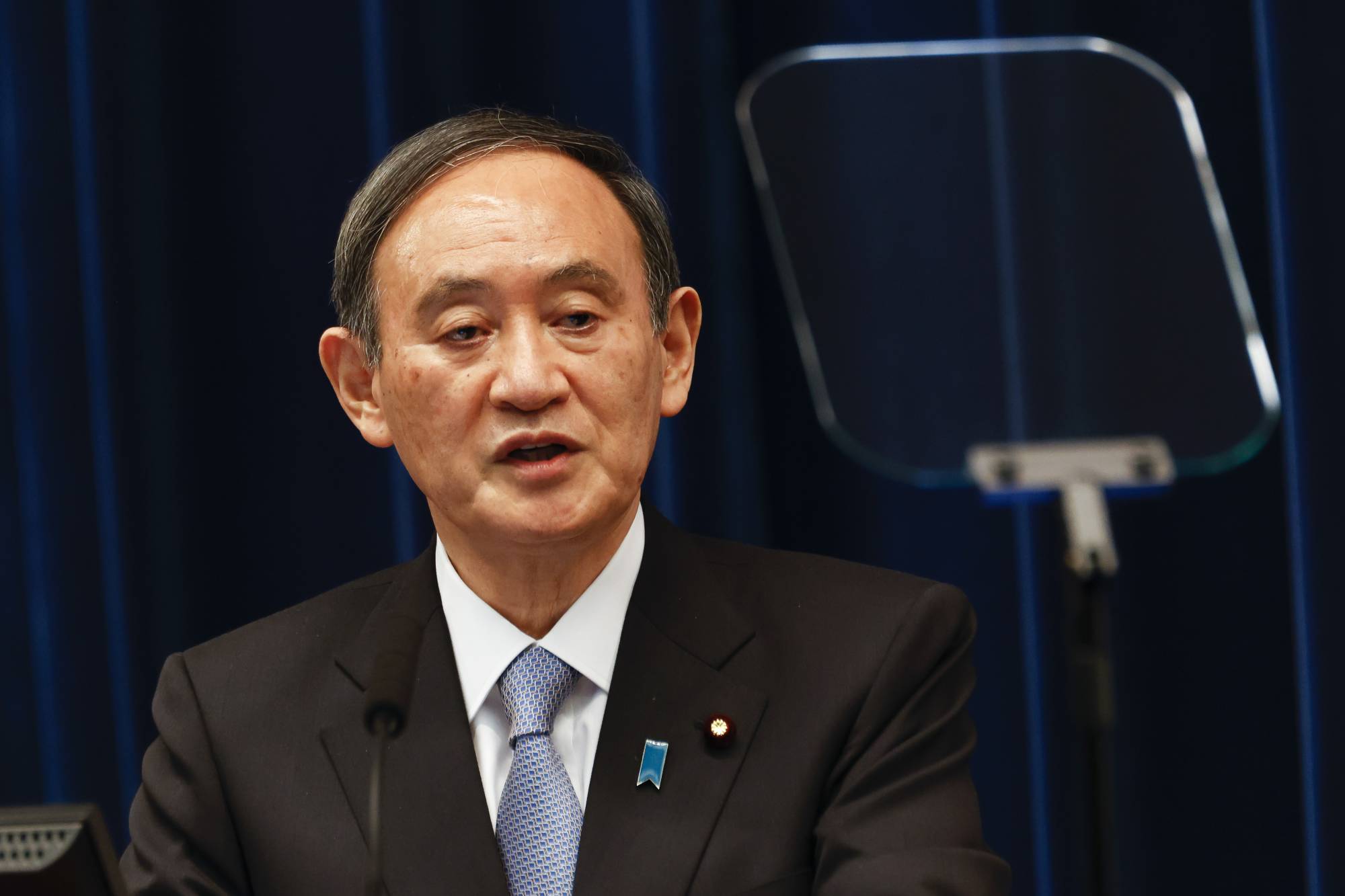 Prime Minister Yoshihide Suga speaks during a news conference in Tokyo on March 18. | Bloomberg