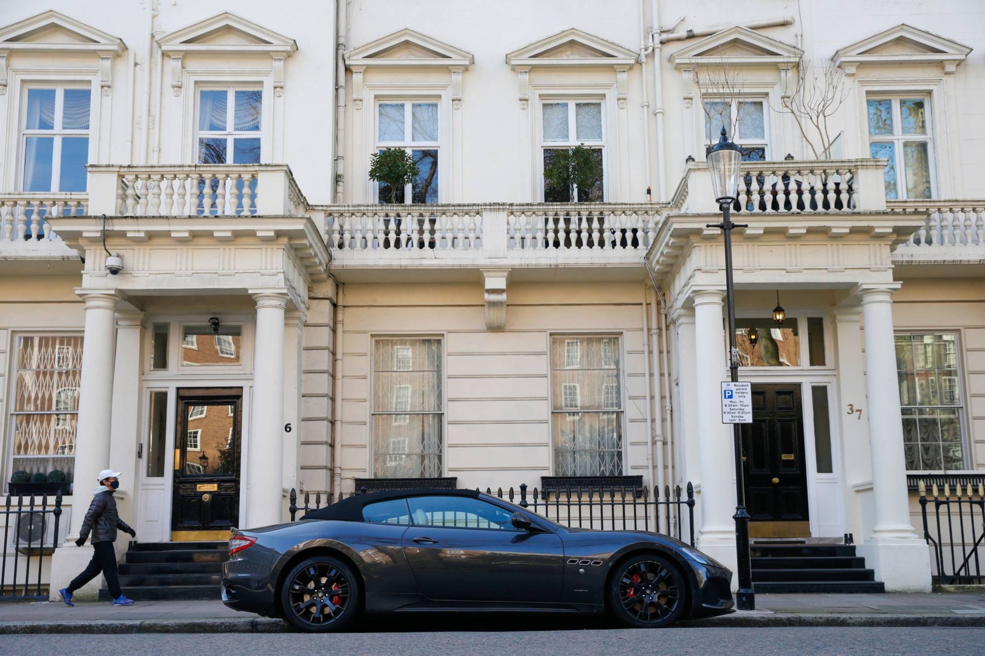 A pedestrian walks past a Maserati in London on March 7. | BLOOMBERG