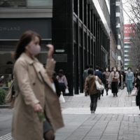Pedestrians walk past stores in the Marunouchi business district of Tokyo on Monday. | BLOOMBERG