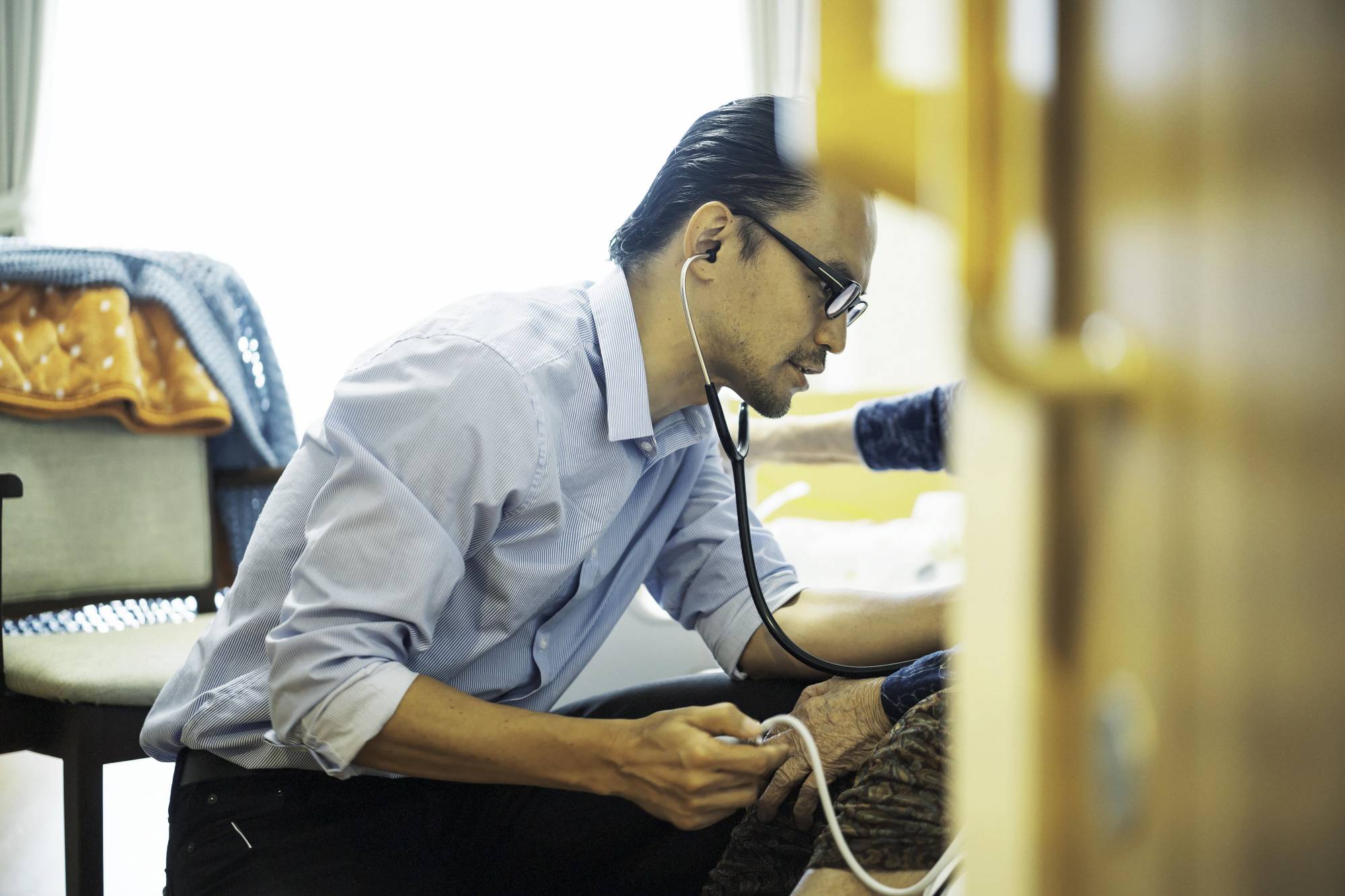 Jun Sasaki, a doctor and the head of Yushokai Medical Corp., a home medical care provider, examines a patient. | Hiroshi Hatano 