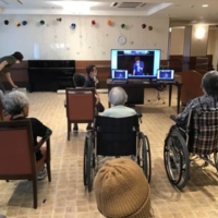 With many recreational activities canceled during the pandemic, nursing care provider Sompo Care Inc., hosts daily events streamed live on large television screens installed in its nursing facilities. | COURTESY OF SOMPO CARE INC.

