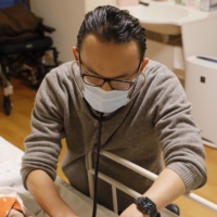 Jun Sasaki, a doctor and the head of Yushokai Medical Corp., a home medical care provider, examines a patient. | Hiroyuki Uchiumi