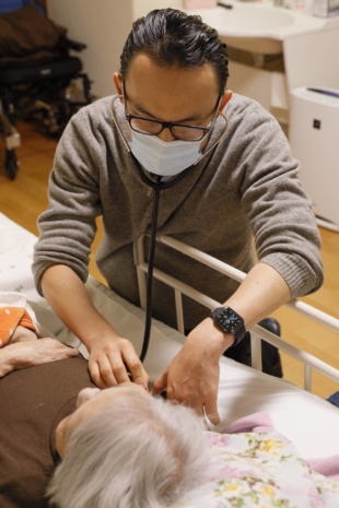 Jun Sasaki, a doctor and the head of Yushokai Medical Corp., a home medical care provider, examines a patient. | Hiroyuki Uchiumi