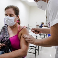A health care worker administers a dose of the AstraZeneca COVID-19 vaccine through the Covax initiative in Asuncion, Paraguay, on Friday.  | BLOOMBERG