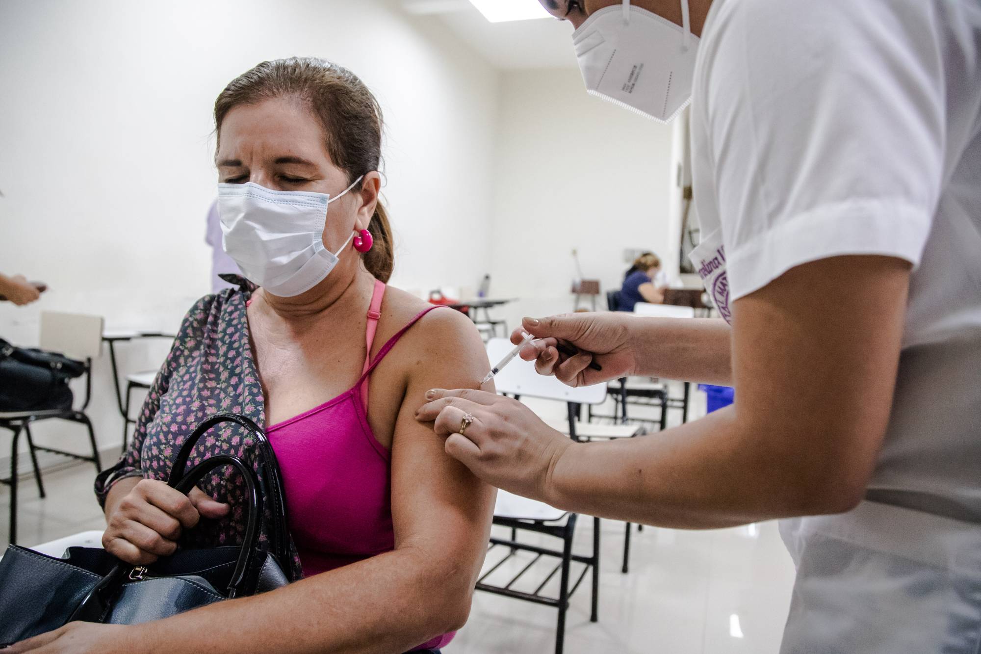 A health care worker administers a dose of the AstraZeneca COVID-19 vaccine through the Covax initiative in Asuncion, Paraguay, on Friday. | Bloomberg