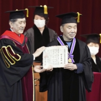 Haruki Murakami (right) receives an award for his distinguished service in the arts from Waseda University President Aiji Tanaka, at the university in Tokyo on Thursday. | KYODO