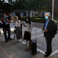 Journalists take pictures and wait to be tested for COVID-19 before attending a news conference in Beijing in May 2020. | REUTERS